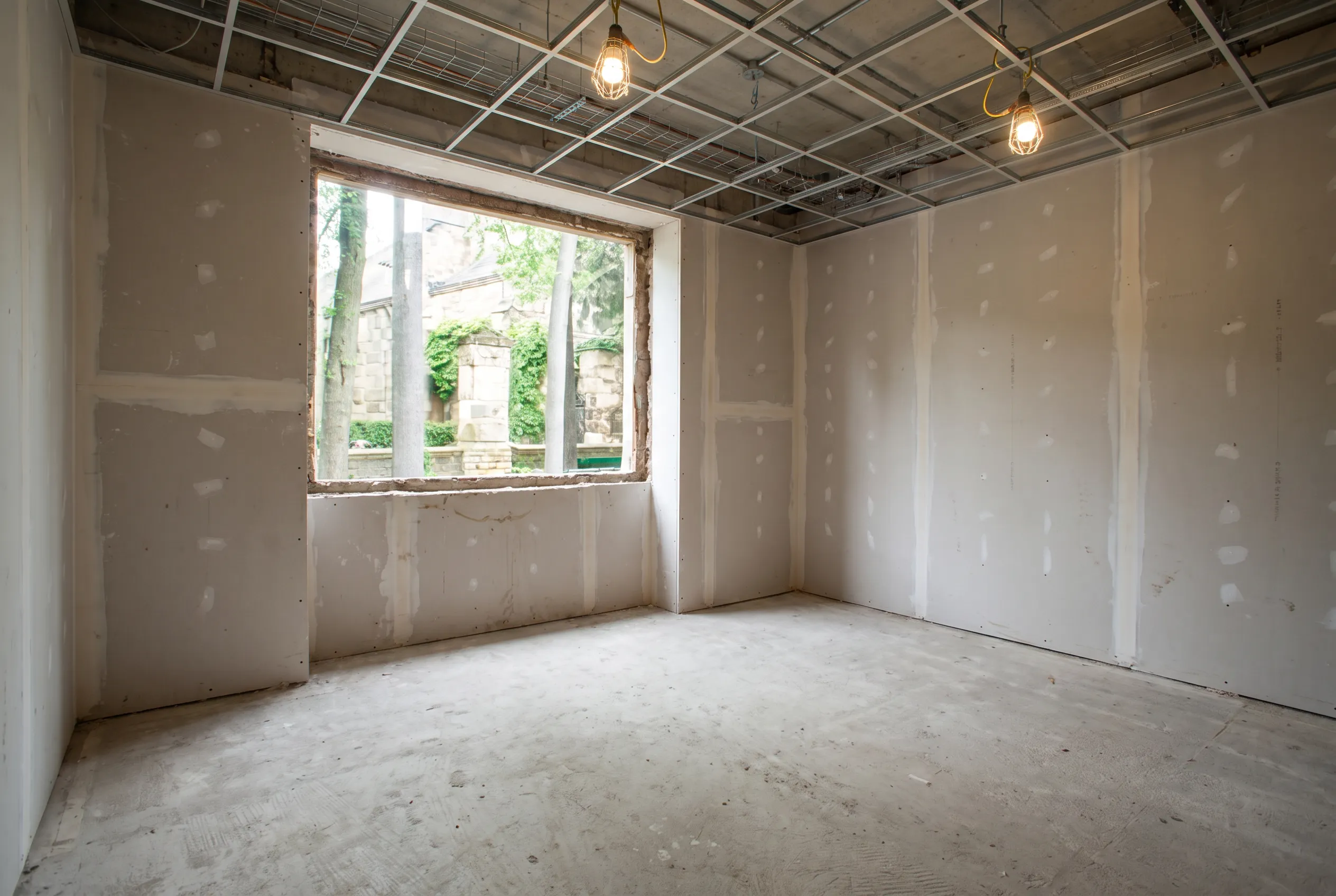 A North York retail unit before conversion, with drop ceilings stained by old roof leaks, fluorescent troffers and thirty years of layered flooring