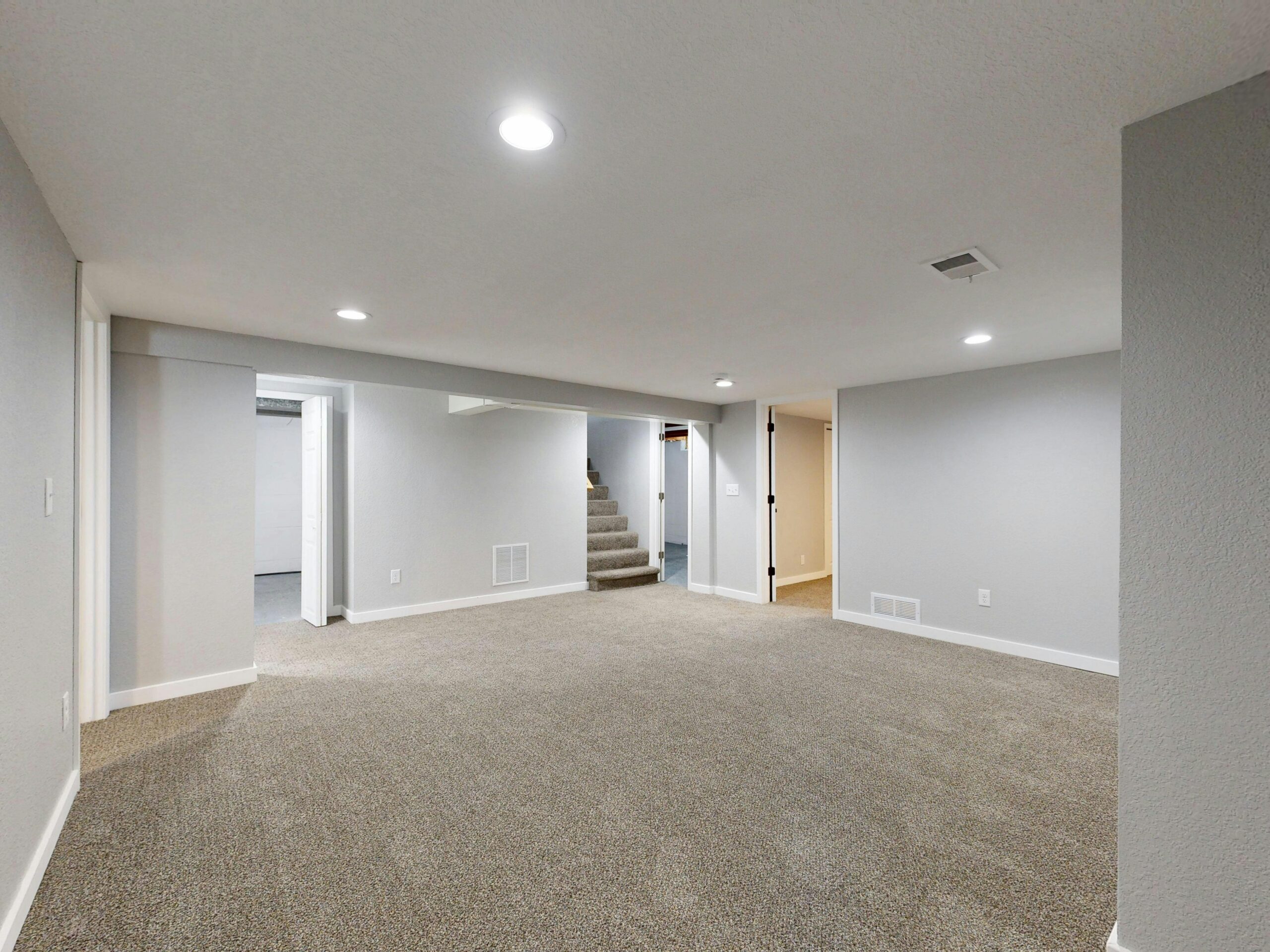 Spacious modern basement with neutral design and carpet flooring, perfect for renovation or real estate listings.