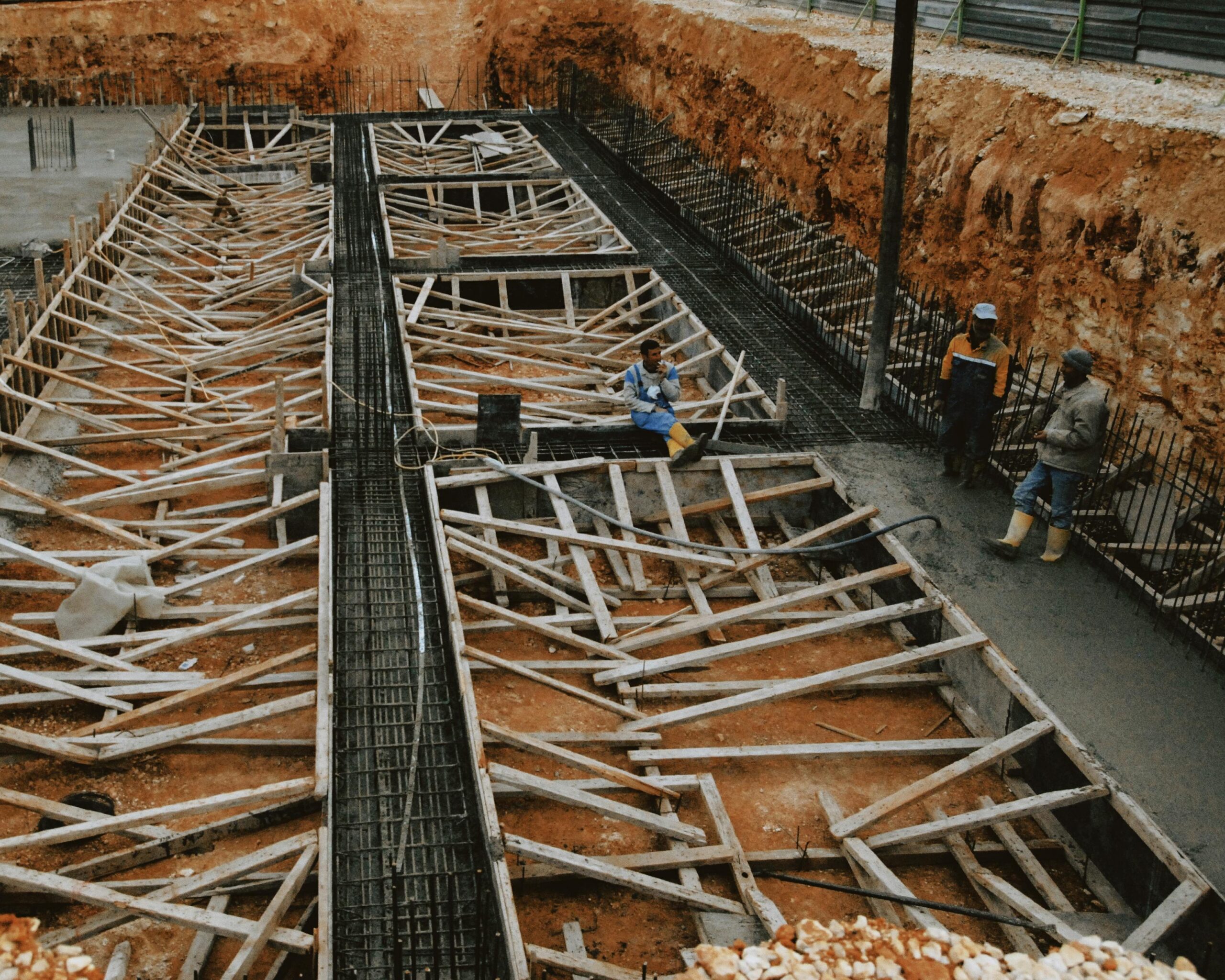 Construction workers at a site with wooden framework in progress, showcasing development.